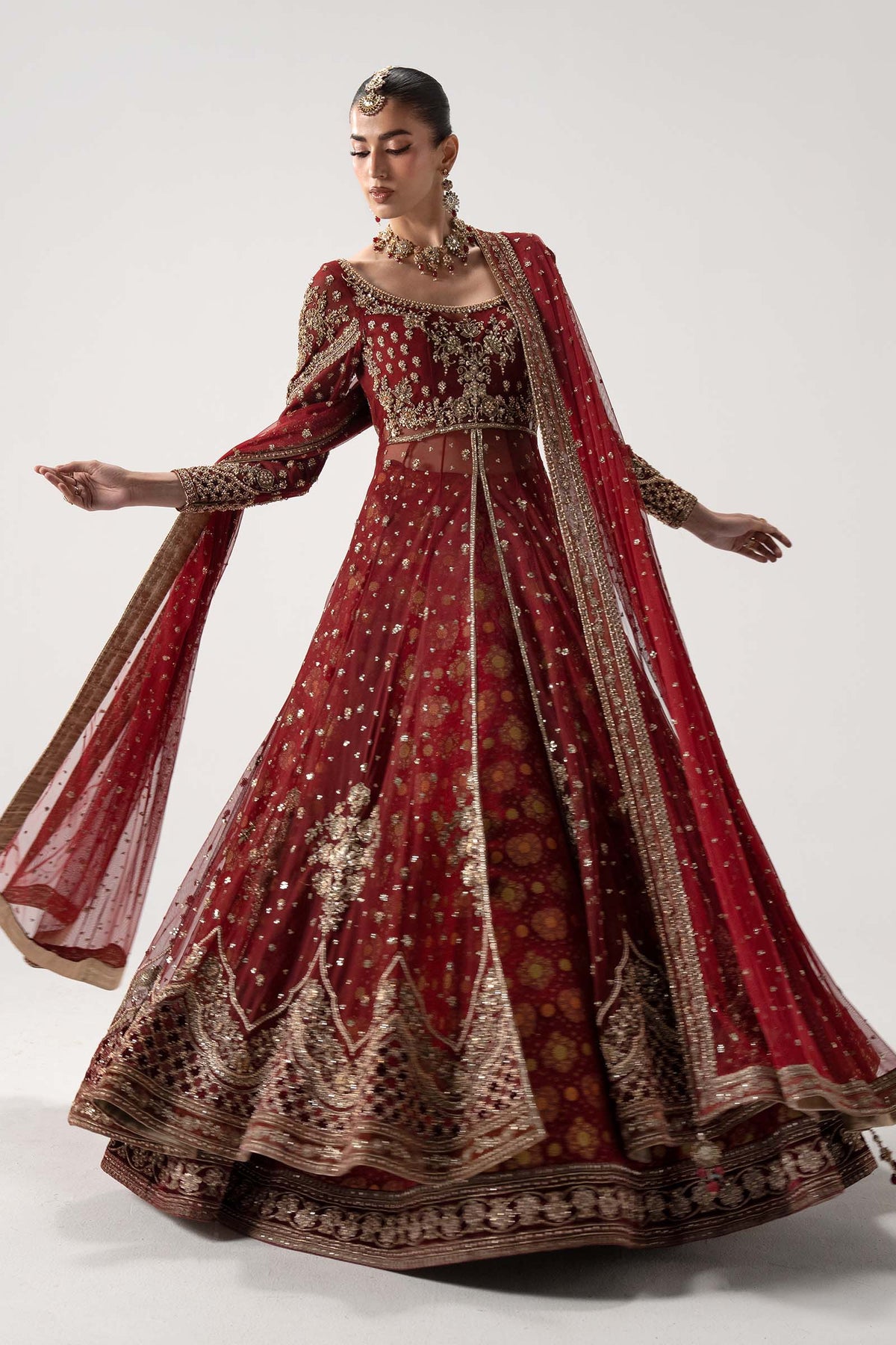 Maria B Bazif 14-panel flared red Pishwas with intricate gold scalloped hem embroidery and matching sheer dupatta for baraat wear