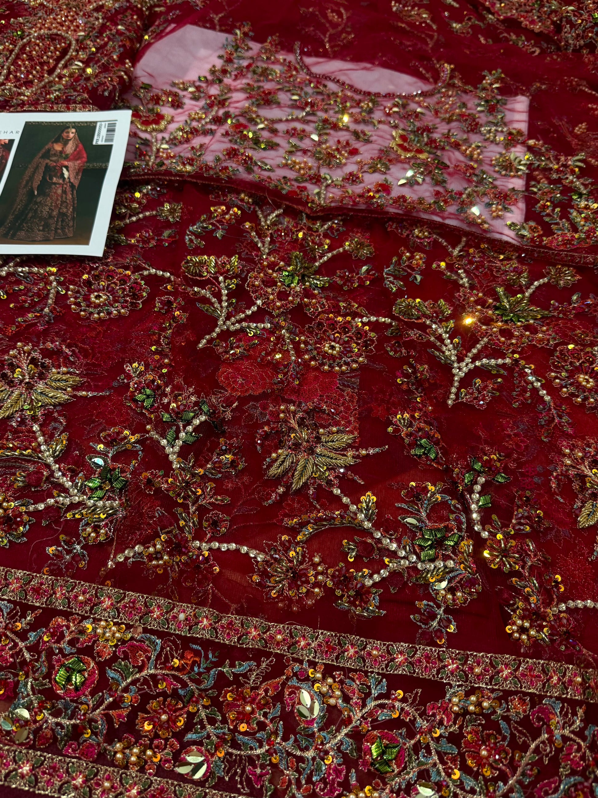 Close-up of premium maroon bridal fabric showcasing intricate hand embellishments, zari embroidery, crystal detailing, and luxury Pakistani couture craftsmanship.