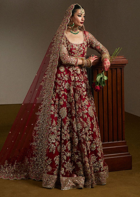 Side view of Hussain Rehar inspired Pakistani bridal maxi in deep maroon with intricate hand embroidery, premium bridal dupatta, luxury wedding outfit, and elegant couture detailing.