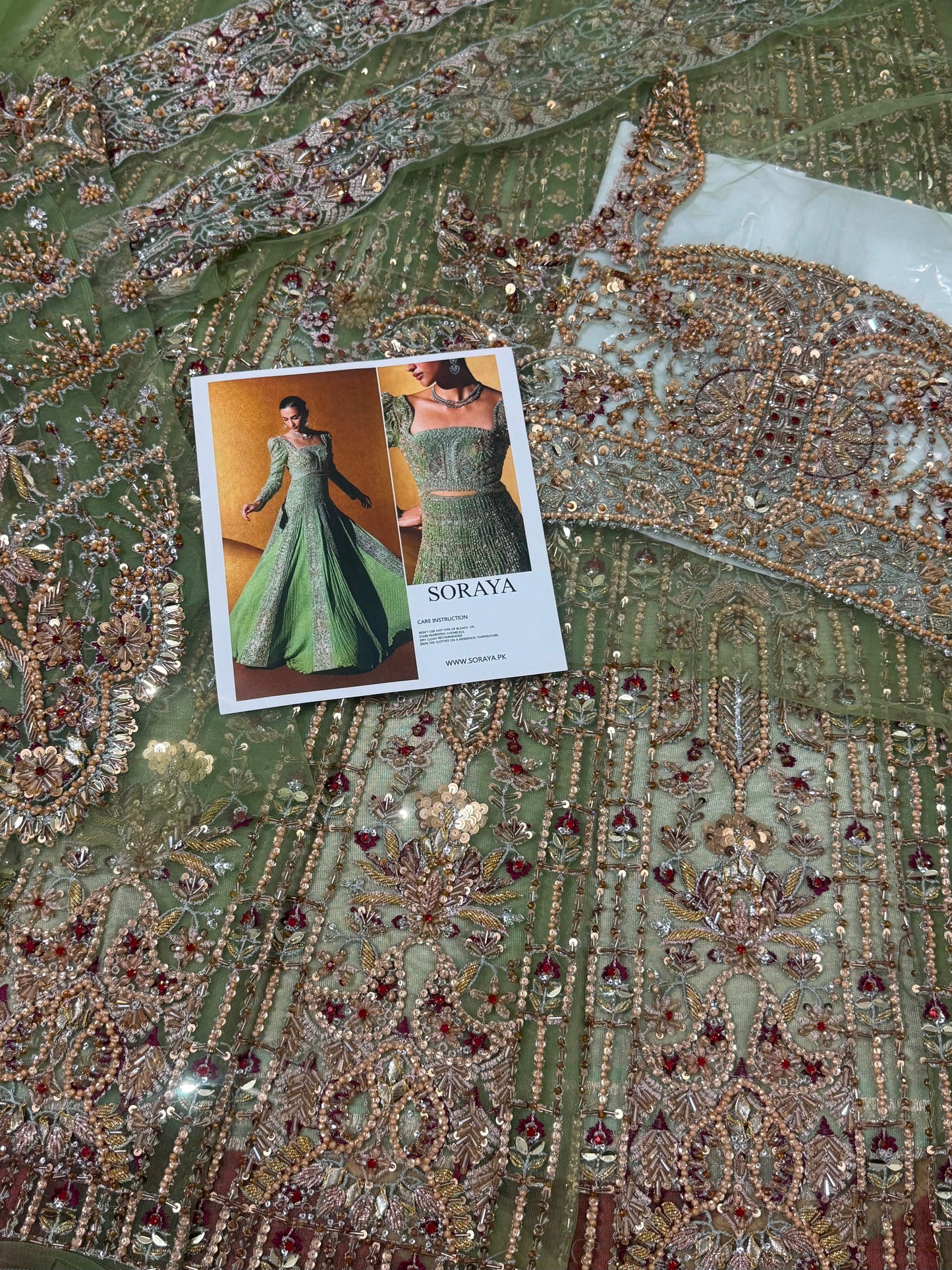 Soraya Celvere luxury Pakistani designer inspired maxi fabric close-up showcasing intricate hand embellishments, crystal stones, premium embroidery, and couture craftsmanship in soft sage green.