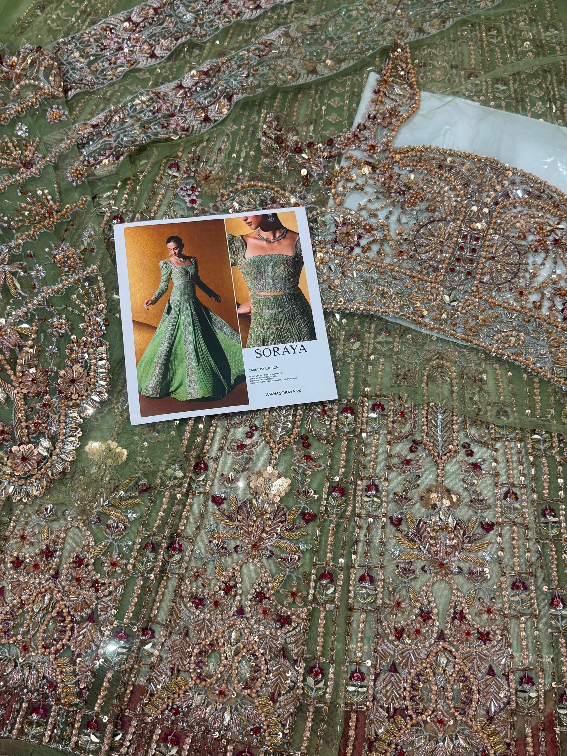 Soraya Celvere luxury Pakistani designer inspired maxi fabric close-up showcasing intricate hand embellishments, crystal stones, premium embroidery, and couture craftsmanship in soft sage green.
